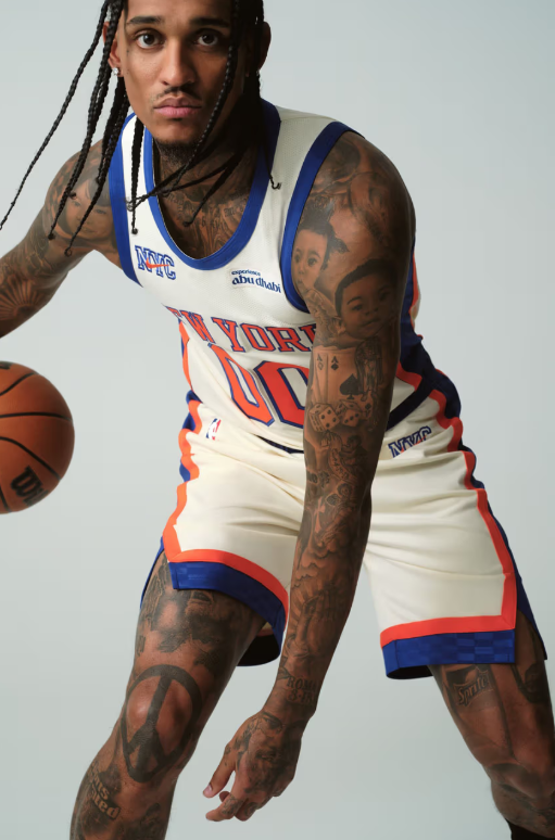 A tattooed man wearing a basketball jersey with the text "Skyforce" holds a basketball.