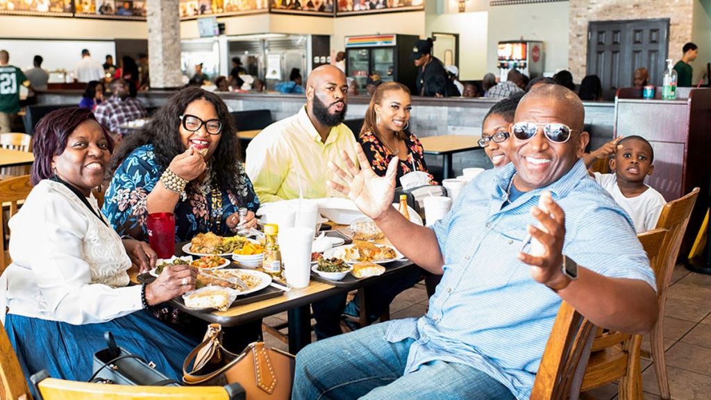 A group of people, including an older woman, a man with a beard, and a young child, enjoying a meal together in a restaurant setting.
