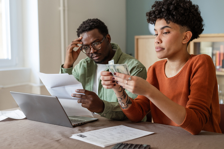 A multicultural couple discussing money problems indoors