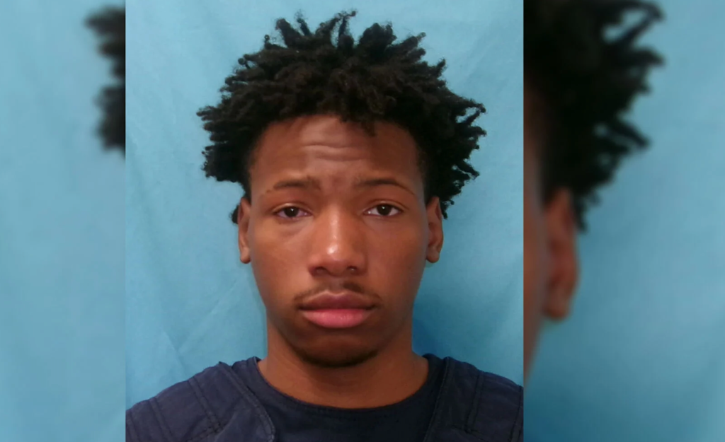 Headshot of a young Black man with short, curly hair and a serious expression against a teal background.