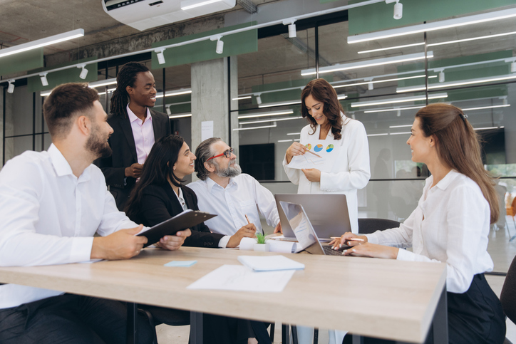 Multiracial business professionals discussing financial data and ideas, working together at an office table